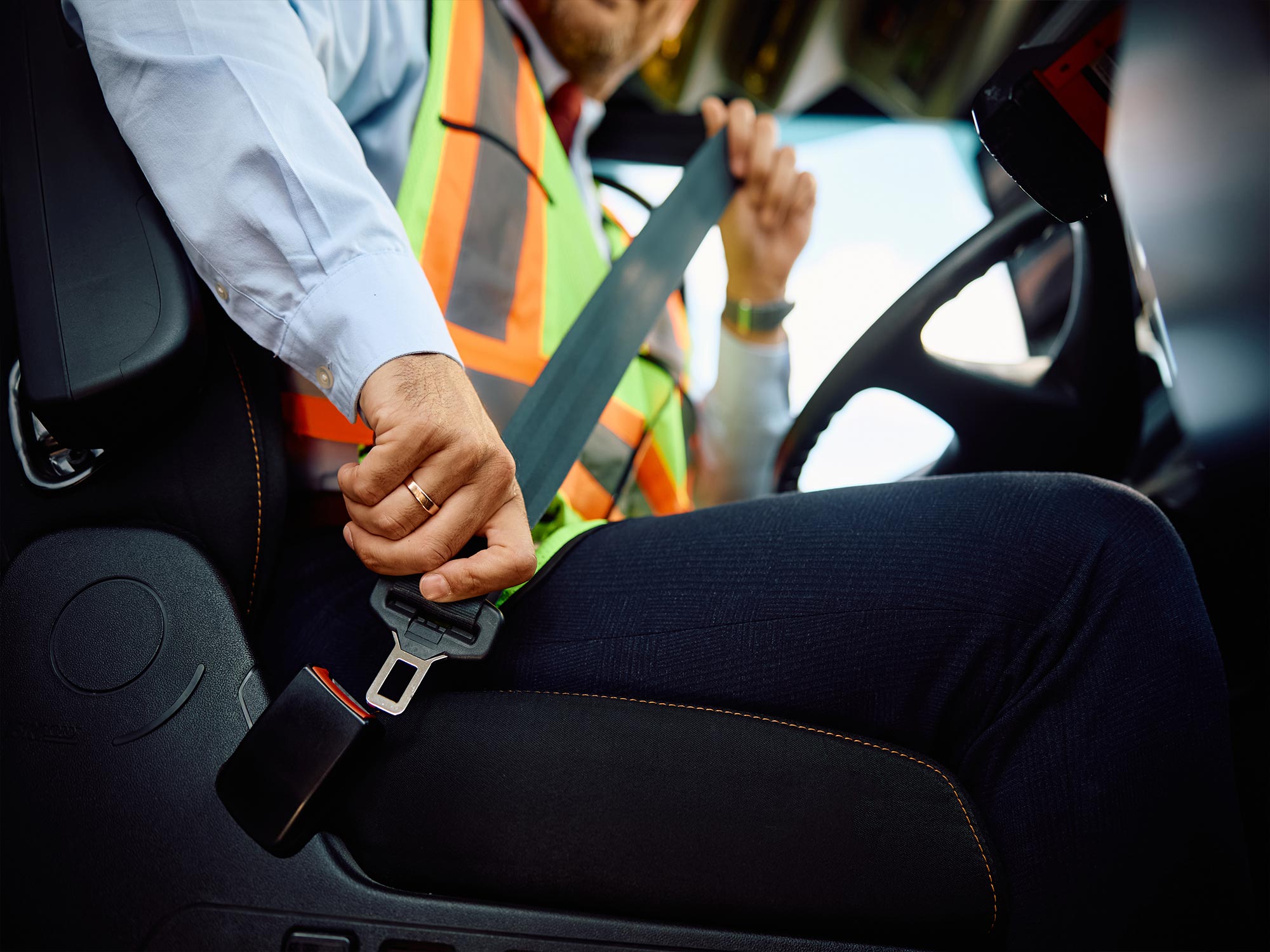 homme qui attache sa ceinture au volant d'une voiture